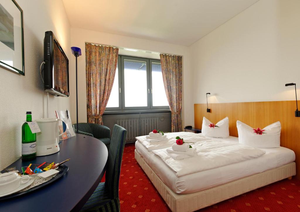 um quarto de hotel com duas camas e uma mesa em Hotel Carat em Erfurt