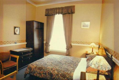 a bedroom with a bed, chair, desk and a television at Murrayfield Park Guest House in Edinburgh