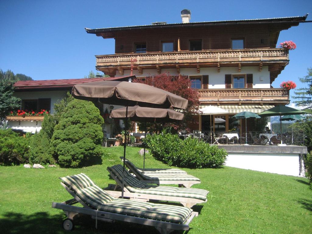a group of chairs and an umbrella in front of a building at Pension Hinterseer in Kitzbühel