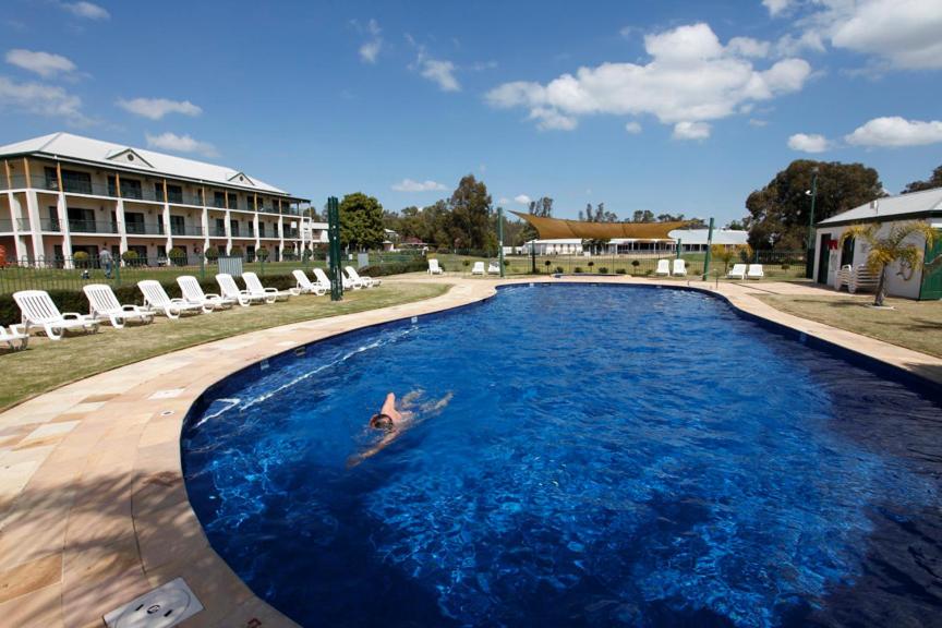 a man is swimming in a pool with a surfboard at Yarrawonga Mulwala Golf Club in Yarrawonga