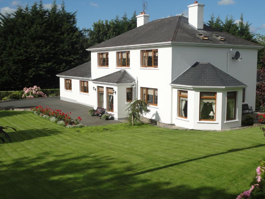 Millhouse B&B في Ballymote: منزل أبيض مع حديقة خضراء