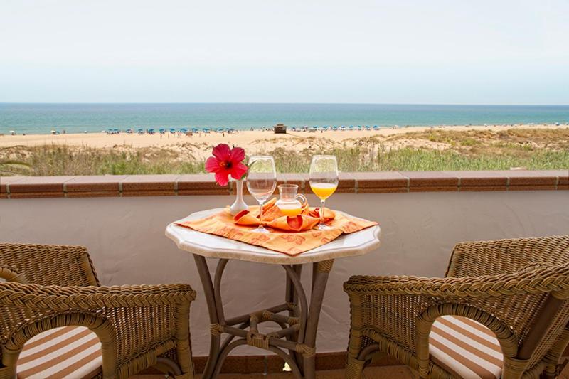 a table with two glasses of wine and a flower on it at Hotel Antonio in Zahara de los Atunes