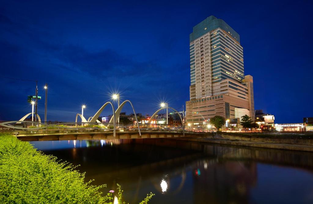 um edifício alto à noite com uma ponte e um edifício em Le Midi Hotel Jungli em Zhongli