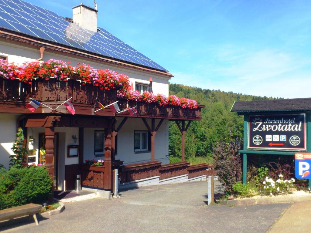 ein Gebäude mit Blumen auf einem Balkon und einem Schild in der Unterkunft Ferienhotel Zwotatal in Zwota