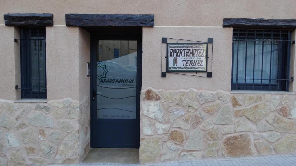 un edificio con una puerta con un cartel. en Apartamentos Turísticos Teruel, en Teruel
