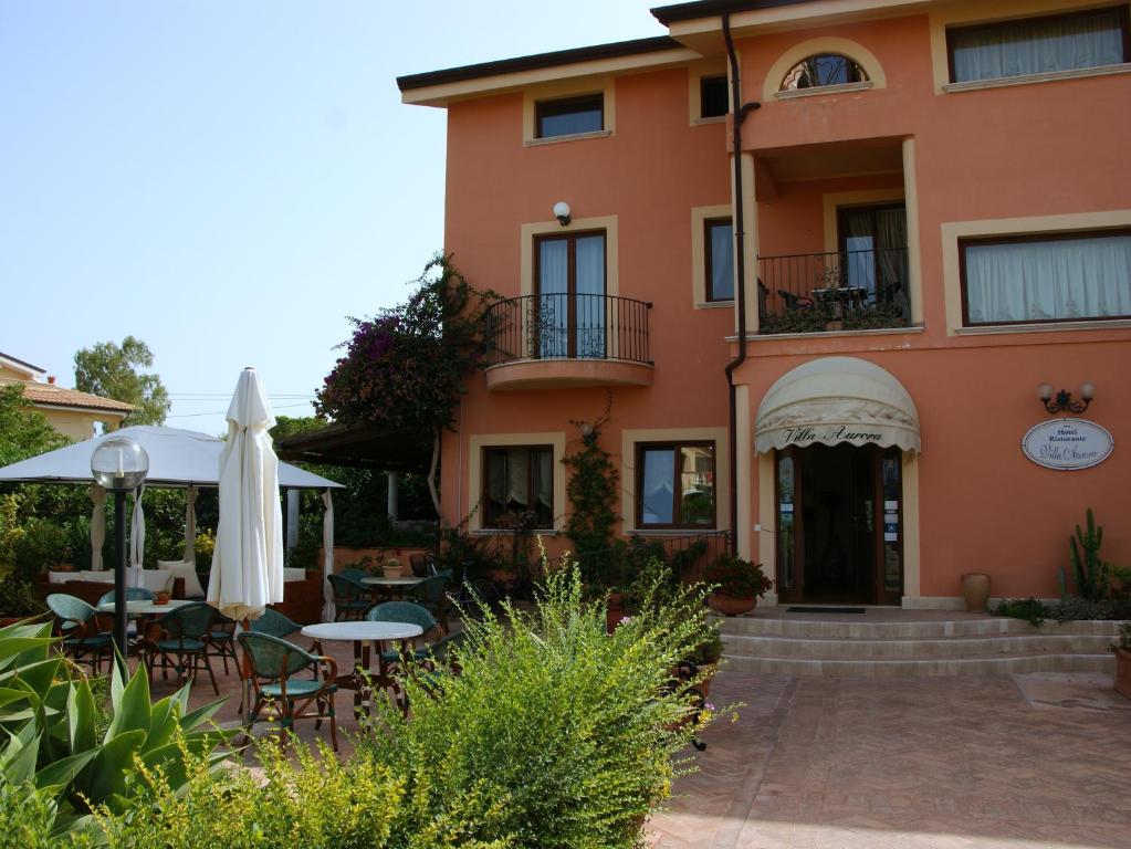 a building with an umbrella and tables and chairs at Villa Aurora in Le Castella