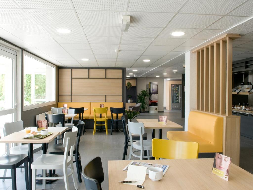 um restaurante com mesas, cadeiras e janelas em B&B HOTEL Saint-Quentin em Saint-Quentin