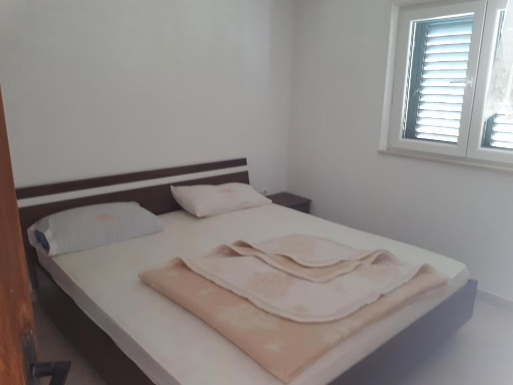 un letto bianco con due cuscini e una finestra di Apartments Marinko a Janjina