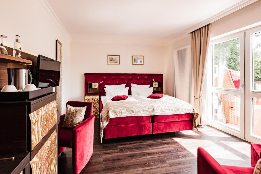 a bedroom with a red bed and a large window at Hotel Kolb in Langeoog
