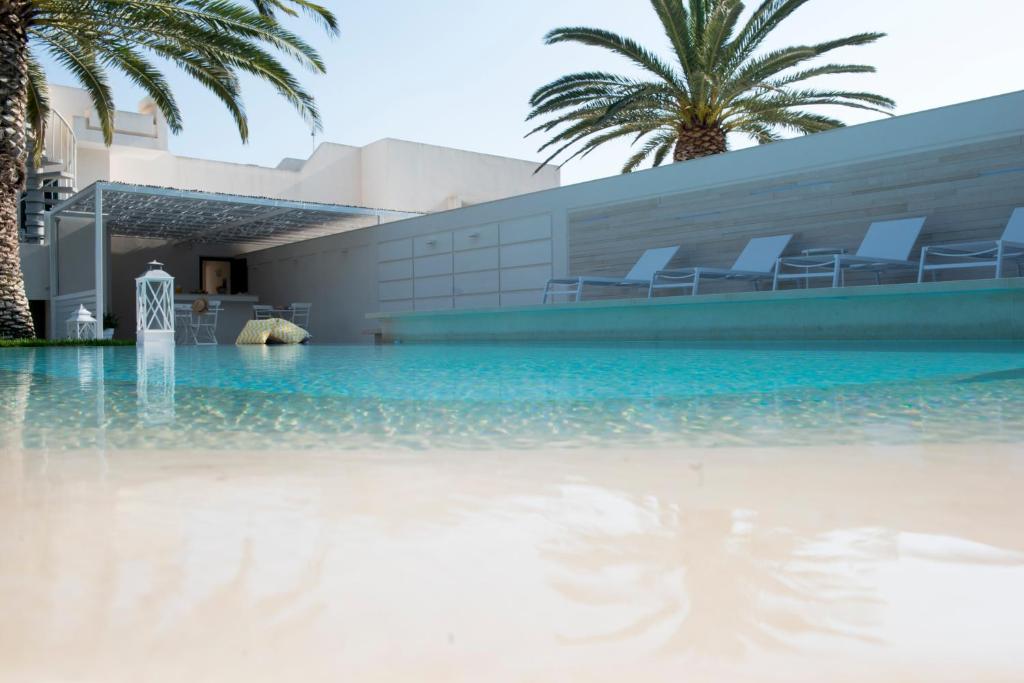 una piscina frente a un edificio con palmeras en Villa Vulcano, en Marina di Ragusa