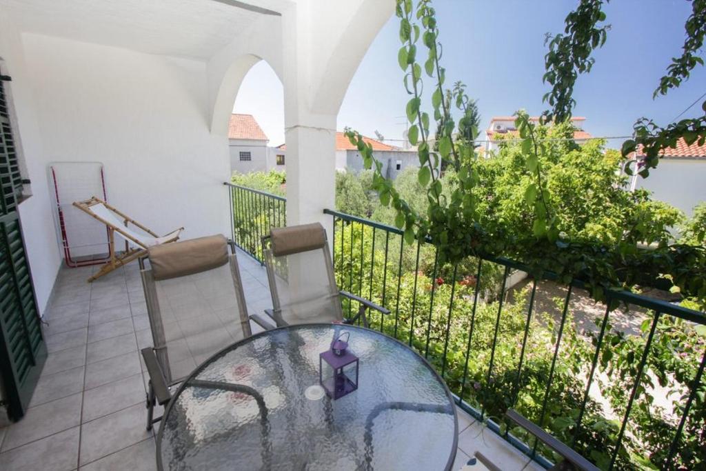 een glazen tafel en stoelen op een balkon bij Apartments Plavica in Zečevo