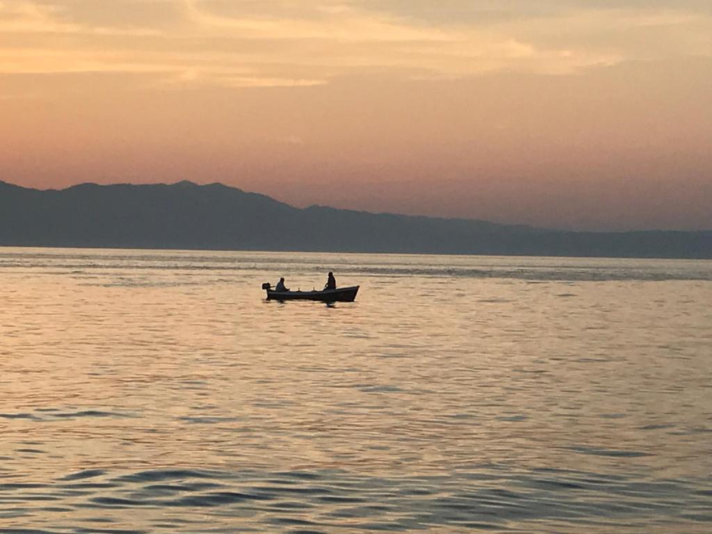 dos personas en un barco en medio del agua en Apartmani Dvojak Njivice, en Njivice