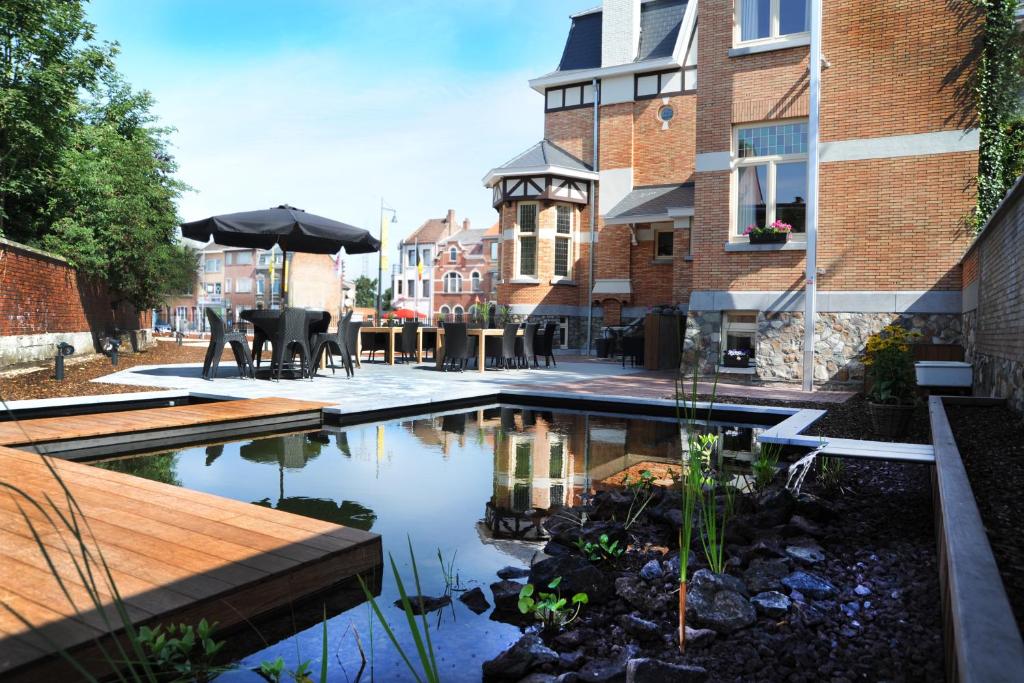 a backyard with a pond with a table and an umbrella at Charmehotel Villa Saporis in Hasselt