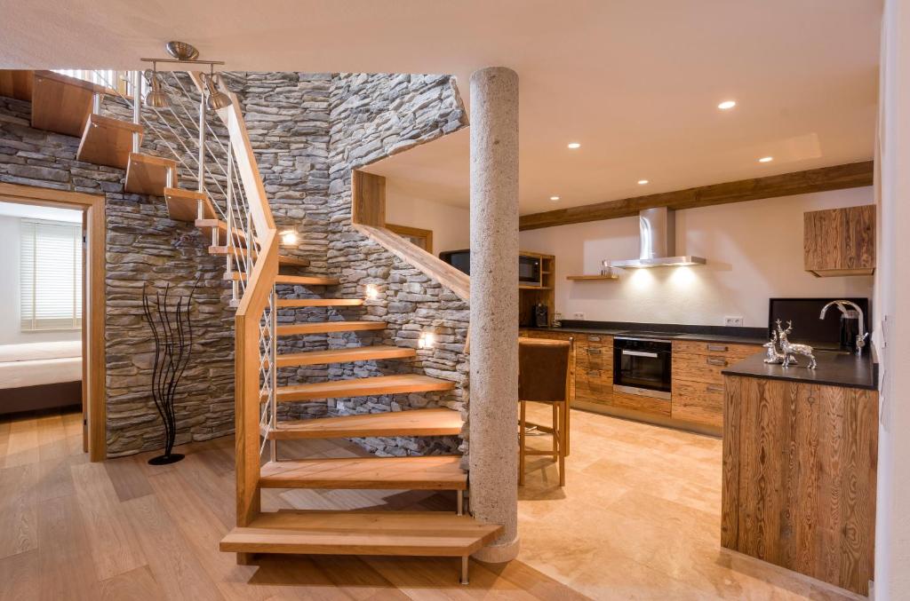 a spiral staircase in a kitchen with a stone wall at Luxus Ferienwohnung Almhütte in Brixen im Thale