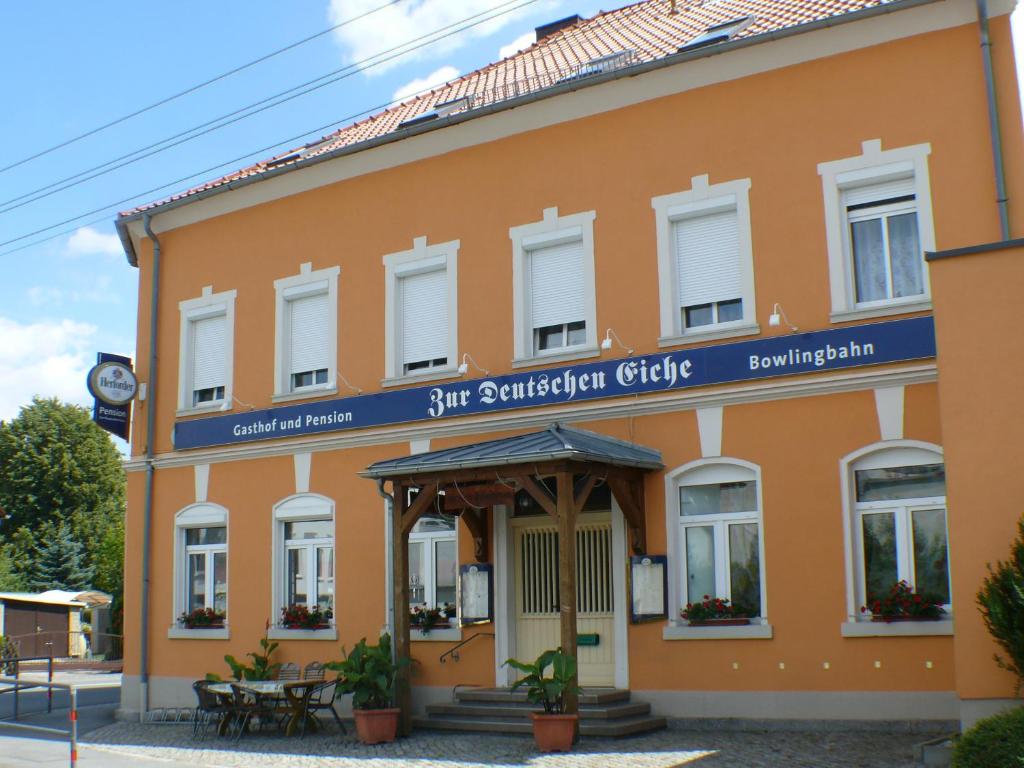 an orange building with a blue sign on it at Zur deutschen Eiche in Großschönau