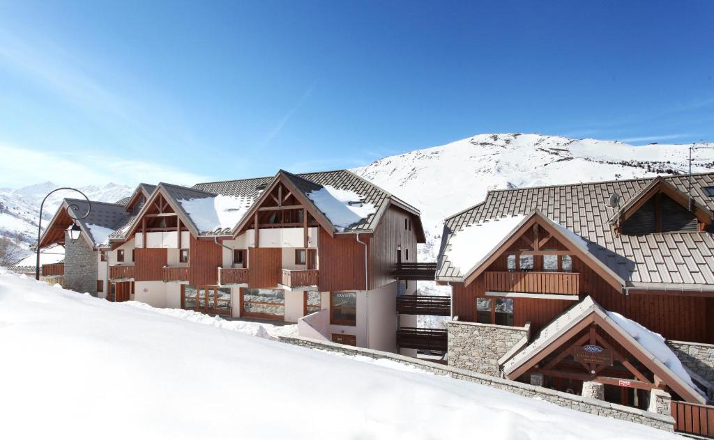 a row of wooden buildings in the snow at Résidence Odalys L'Ecrin des Neiges in Valmeinier
