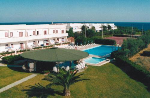 a large building with an umbrella and a swimming pool at Residence Club Barbara in Ostuni
