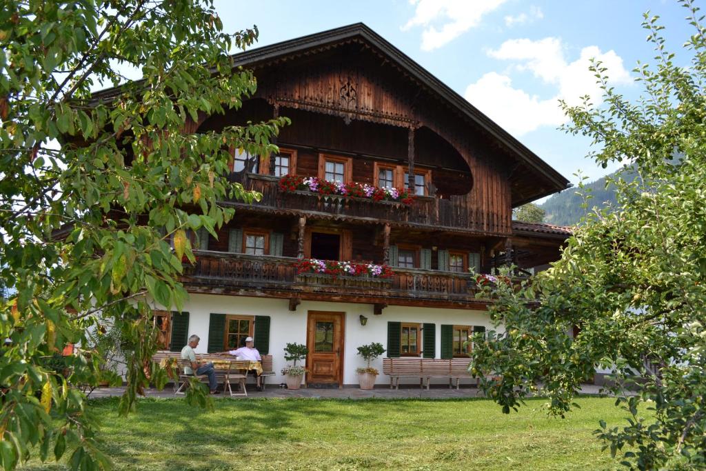 a house with people sitting at a table in front of it at Böglhof in Stumm