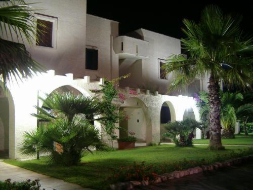a large white building with palm trees in front of it at Residence Club Barbara in Ostuni