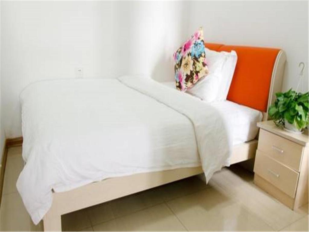 um quarto com uma cama branca e uma cabeceira laranja em Xi'an Helen Apartment em Xi'an