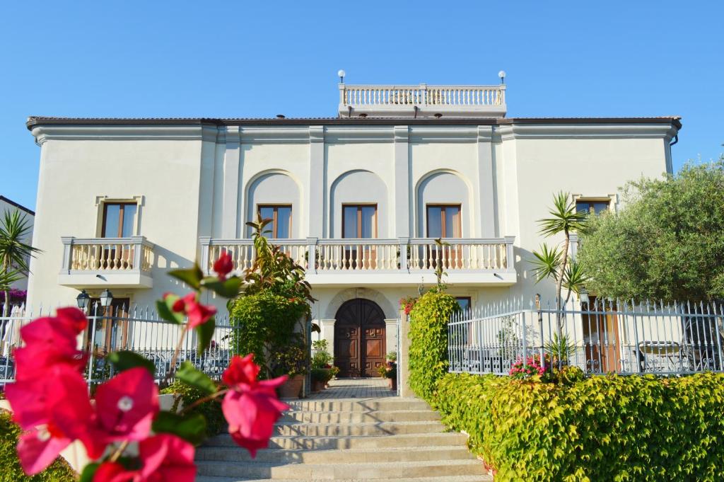 una casa blanca con flores rojas delante en Hotel Villa Cerelis, en Diamante