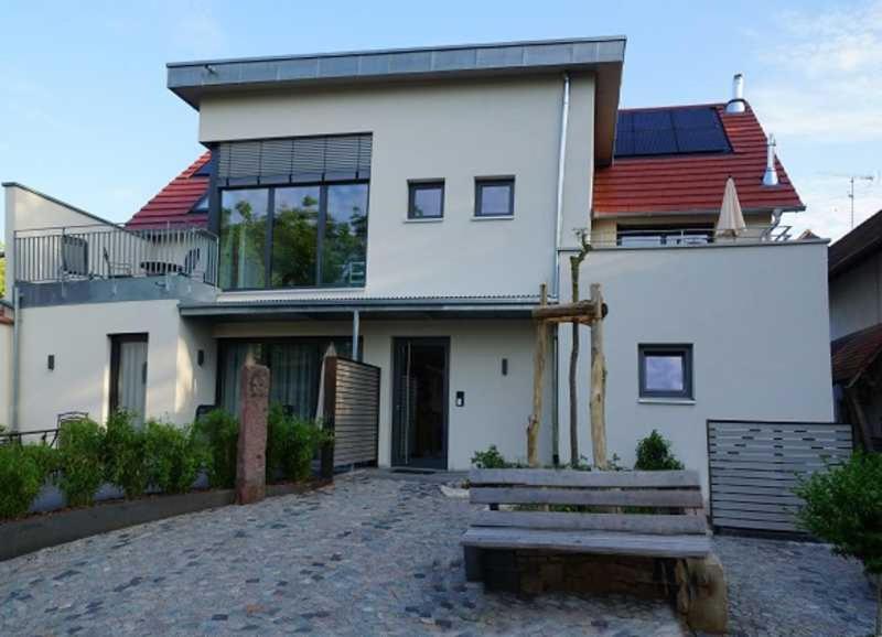 une maison blanche avec un banc devant elle dans l'établissement Gaestehaus Herzig, à Oberrimsingen