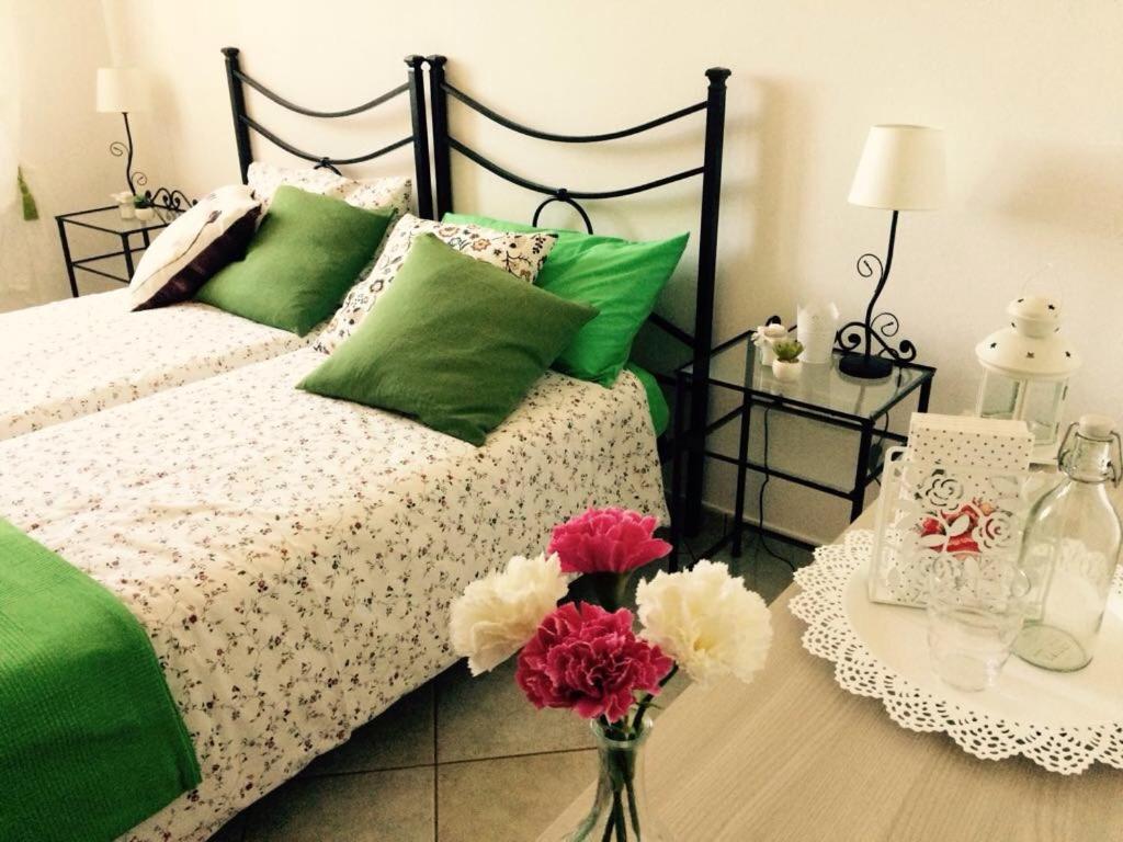 Una cama con almohadas verdes y rosas y una mesa con flores. en Appartamenti Monte Alago, en Nocera Umbra