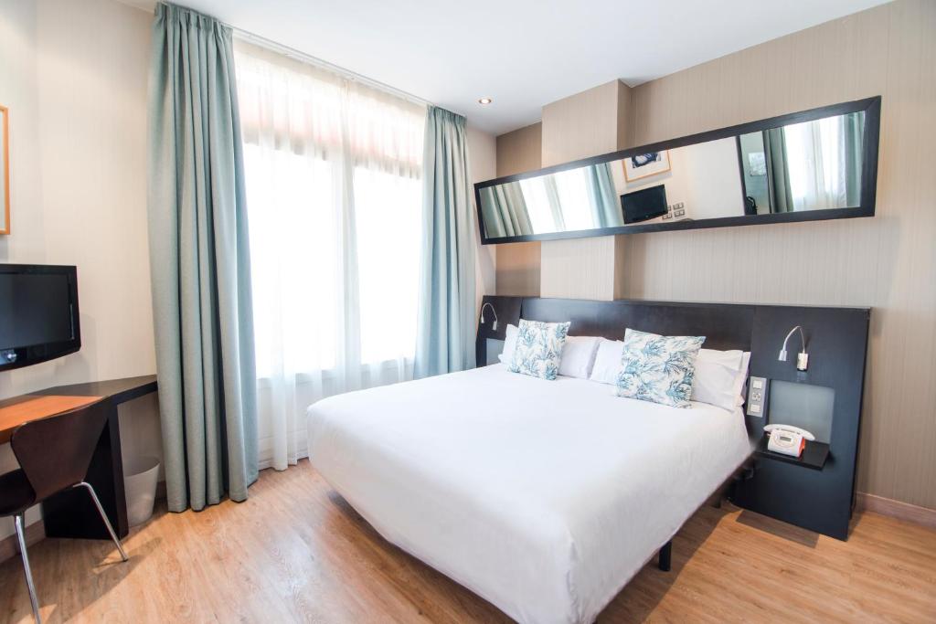 a bedroom with a large white bed and a television at Petit Palace Ruzafa in Valencia