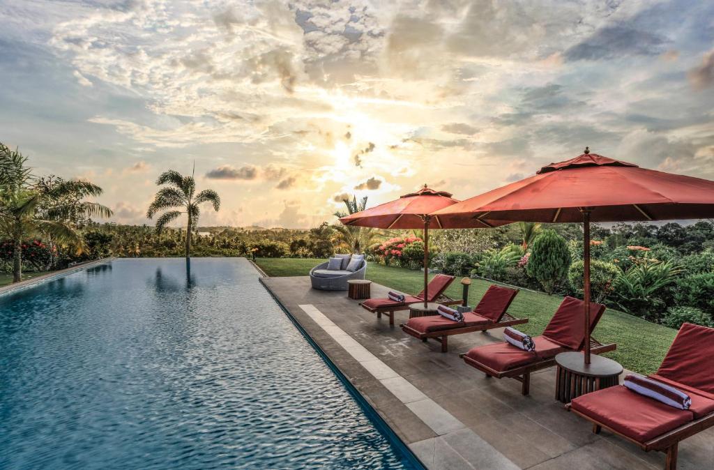 a swimming pool with chairs and umbrellas next to a pool at Villa Mayurana by Edwards Collection in Koggala