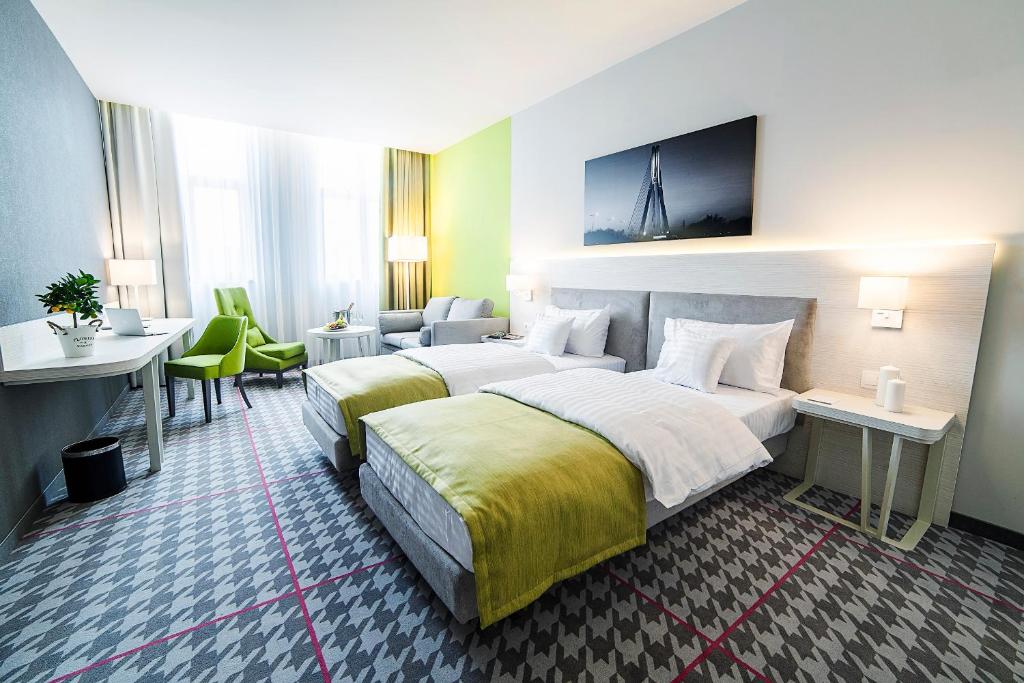 a hotel room with two beds and a desk at Hotel Metropolitan in Rzeszów