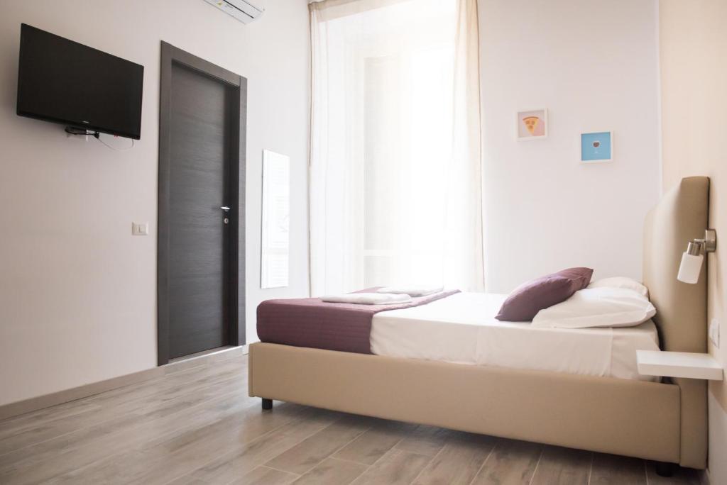 a bedroom with a bed and a flat screen tv at B&B Università in Naples