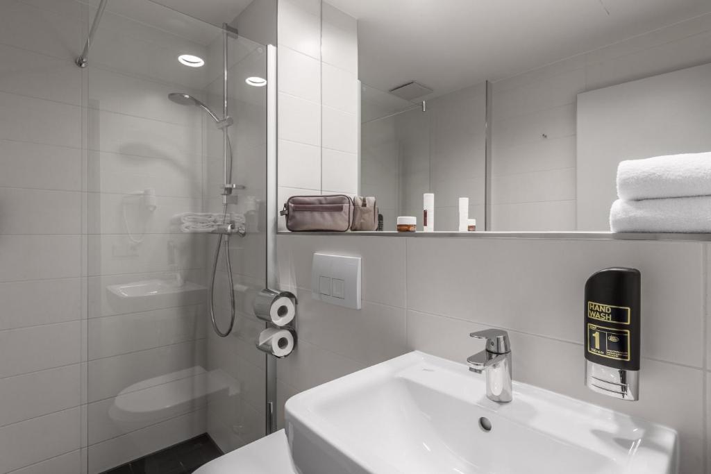 a white bathroom with a sink and a shower at Serways Hotel Bruchsal West in Forst