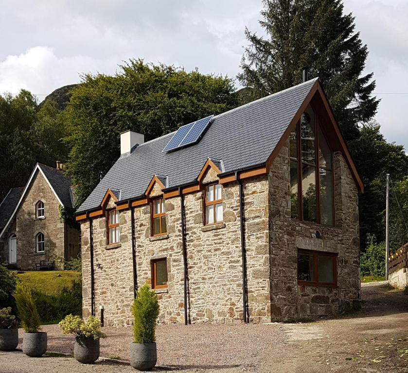 a stone house with solar panels on the roof at The Armoury in Glenfinnan