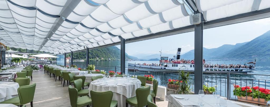 ein Restaurant mit Blick auf das Wasser und ein Boot in der Unterkunft Villa Belvedere Como Lake Relais in Argegno