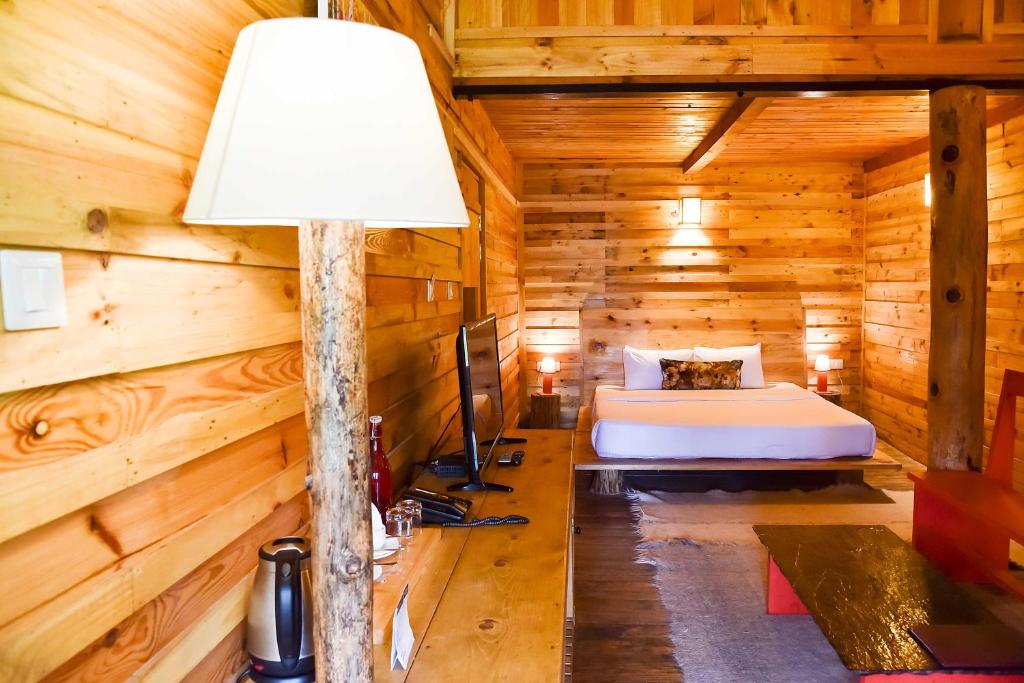 a bedroom in a log cabin with a bed and a lamp at Suro Treehouse Resort in Shogi