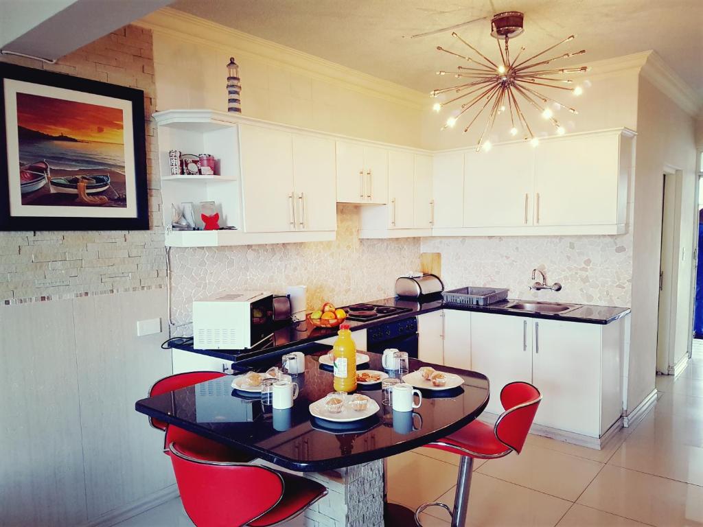 a kitchen with a table and red chairs in it at Dumela Margate Flat No 11 in Margate