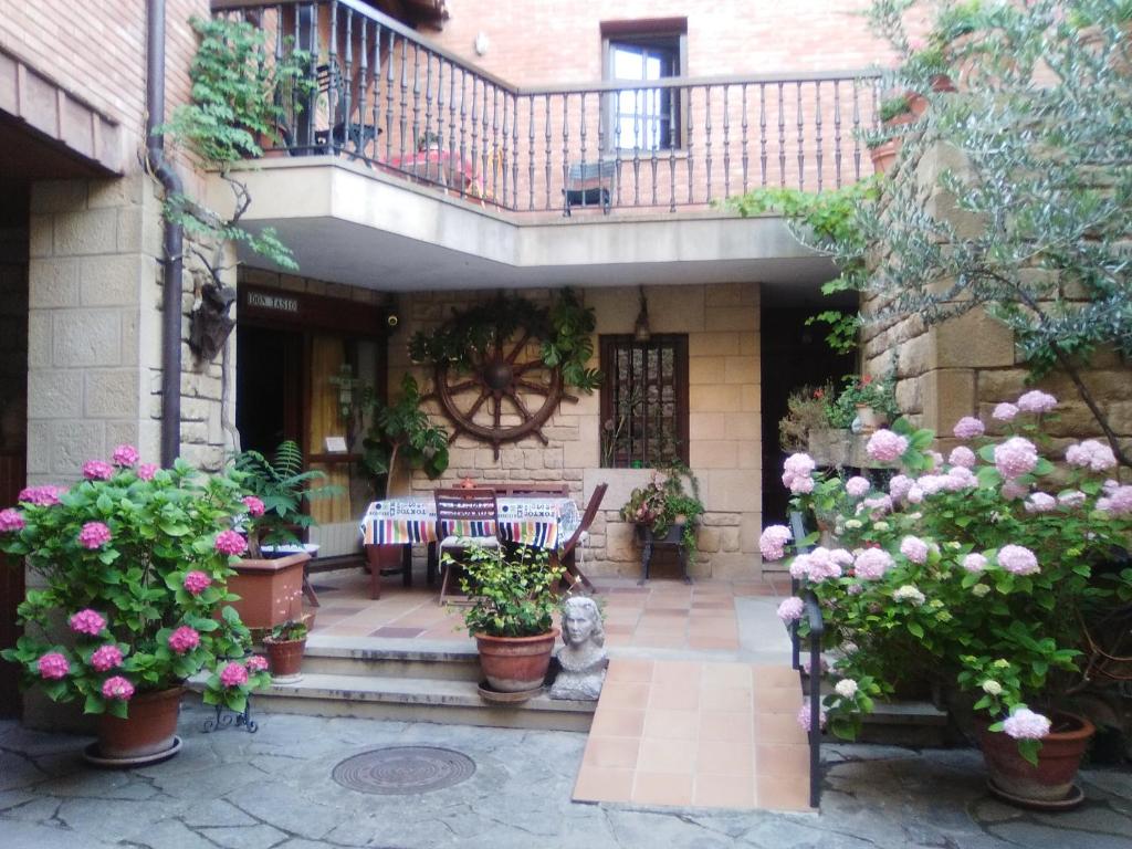 un patio con flores y mesas y un balcón en Casa Rural Erletxe, en Laguardia