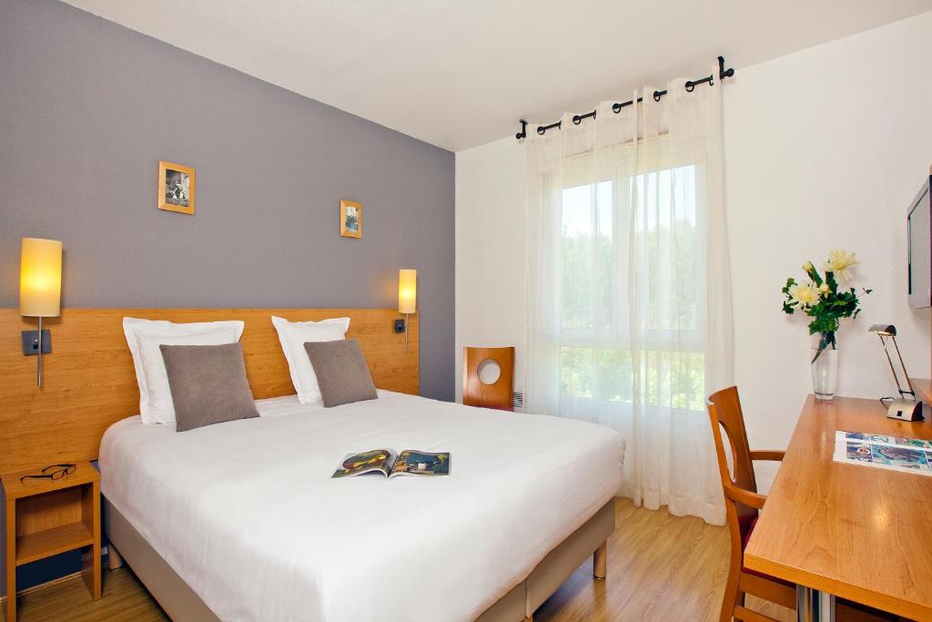 une chambre avec un grand lit blanc et un bureau dans l'établissement Séjours & Affaires Annecy Le Pont Neuf, à Annecy