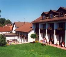 un grupo de personas sentadas fuera de un edificio en Hotel Am Lingelbach, en Knüllwald