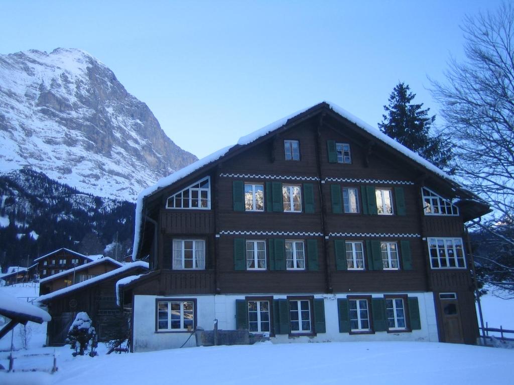 una gran casa de madera en la nieve con una montaña en Chalet Bärgblick, en Grindelwald