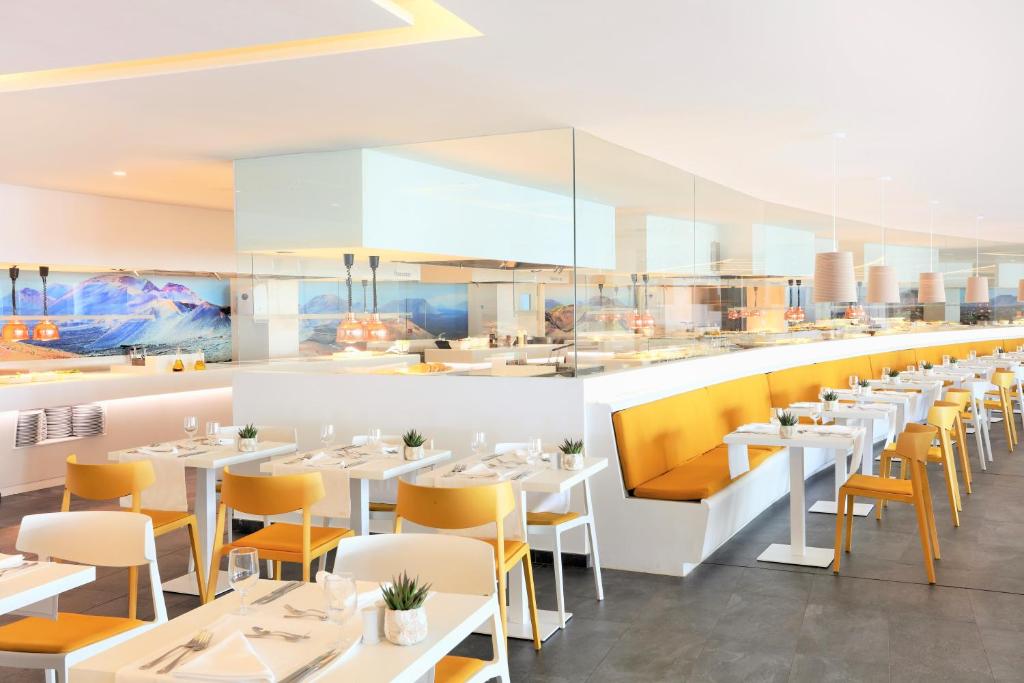 a restaurant with white tables and yellow chairs at Iberostar Selection Lanzarote Park in Playa Blanca