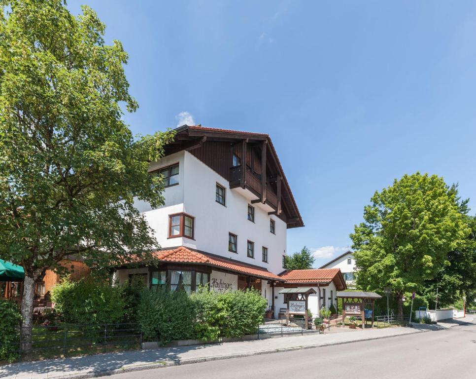 a white building with a brown roof on a street at Hotel Hachinger Hof in Oberhaching