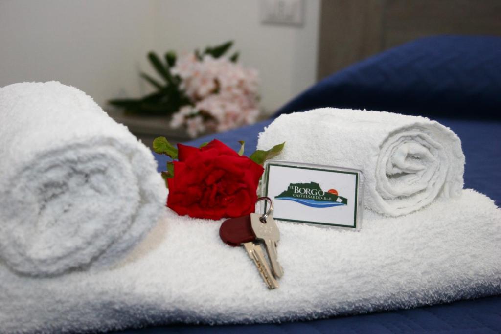カステルサルドにあるIl Borgoのタオル(鍵付)とベッドの上にバラを用意しています。