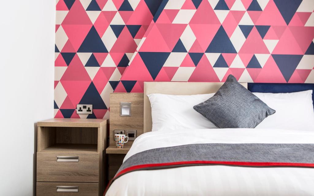 ein Schlafzimmer mit einer geometrischen rosa und blauen Wand in der Unterkunft Cityroomz Edinburgh in Edinburgh