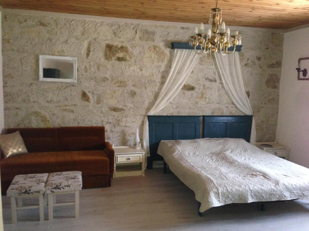 a bedroom with a bed and a couch and a chandelier at Szitakötő Apartman in Demjén