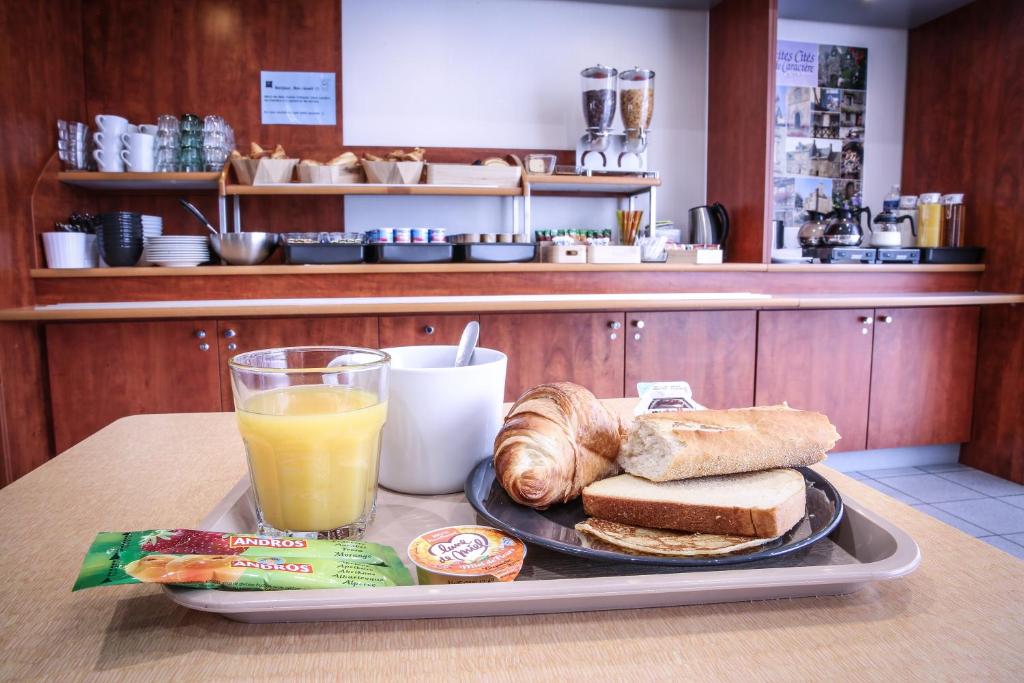 a tray with a plate of breakfast food and a glass of orange juice at Hotel Ibis Budget Rennes Cesson in Cesson-Sévigné