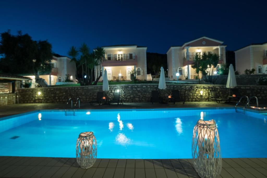 a swimming pool at night with a house in the background at Dallas Studios in Syvota