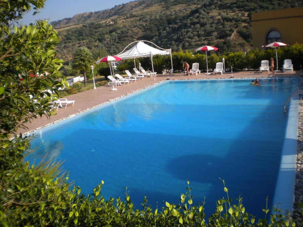 ein großer blauer Pool mit Stühlen und Sonnenschirmen in der Unterkunft Tenuta Agrituristica Castellesi in Squillace