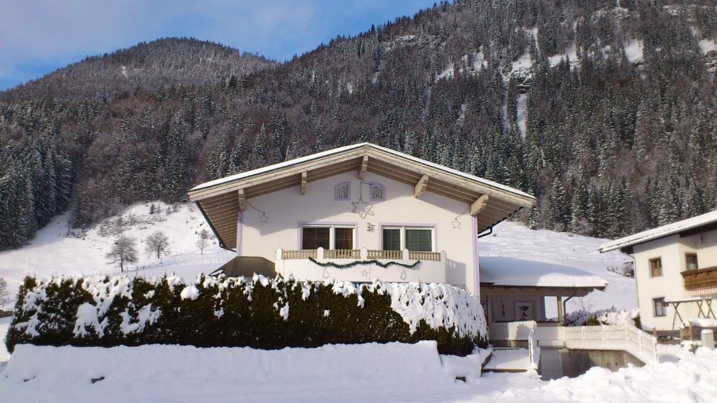 a house in the snow in front of a mountain at Villa Rupert und Jasmin Hauser in Sankt Ulrich am Pillersee