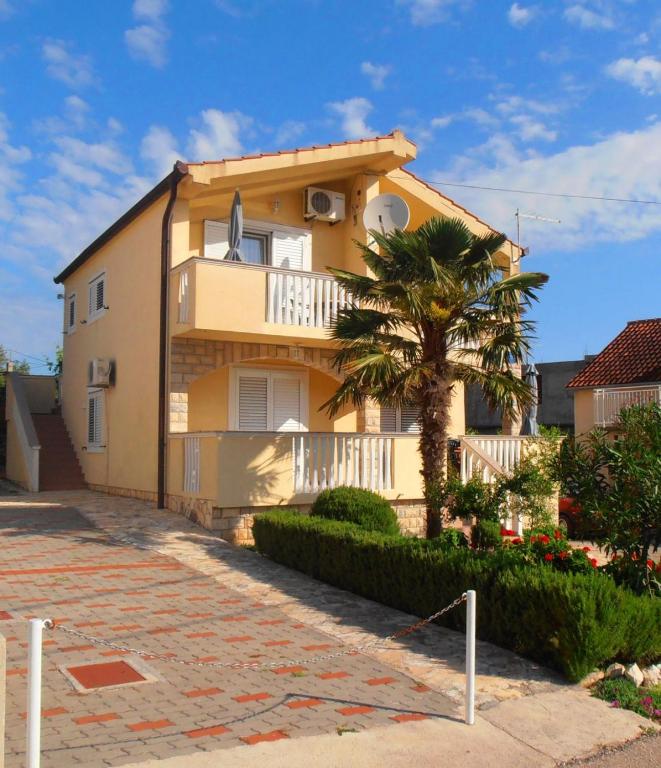 a yellow house with a palm tree in front of it at Apartments Barbara in Banj